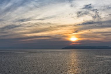 Suda yansıma ile gizemli gökyüzü ile deniz üzerinde günbatımı