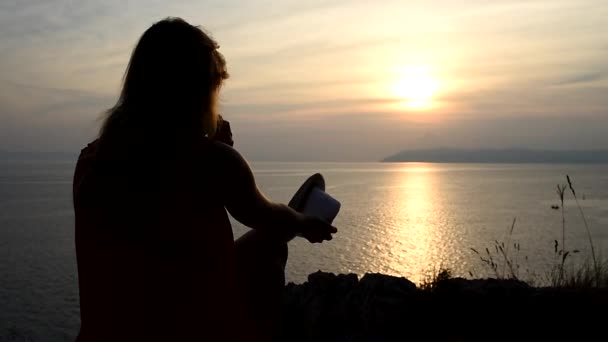 Mädchen beobachtet Sonnenuntergang über dem Meer und denkt über den Sinn des Lebens nach — Stockvideo