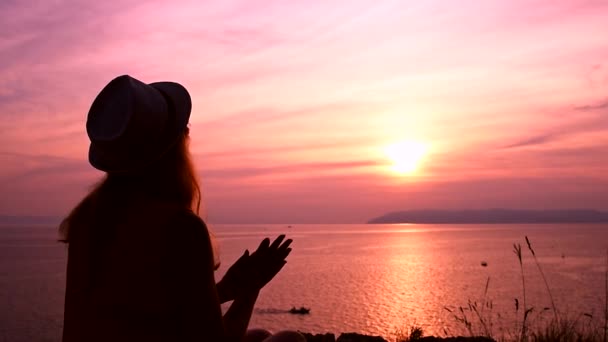 Дівчина дивиться захід сонця над морем думаючи про сенс життя — стокове відео