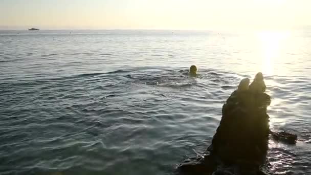 Meisje zwemt in de warme zee bij zonsondergang — Stockvideo