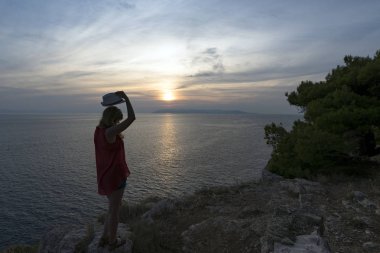Adriyatik Denizi üzerinde günbatımı arka planda bir kızın silüeti