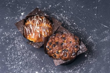 Yakından kapatın. Koyu anahtar. Siyah kağıt içinde çikolata parçaları ile Muffins