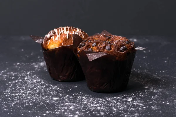 Chiudete. Chiave oscura. Muffin con pezzi di cioccolato in carta nera — Foto Stock