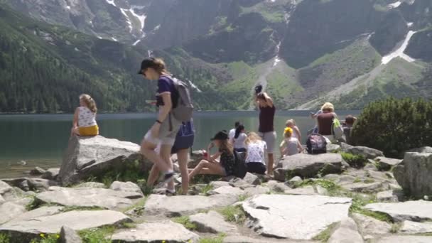 Poland, Zakopane, Tatras June 2019. Туристы на берегу горного озера — стоковое видео