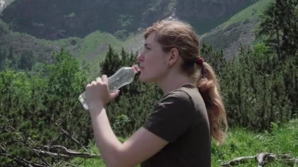 Jong meisje drinkwater na het beklimmen van de bergen — Stockvideo
