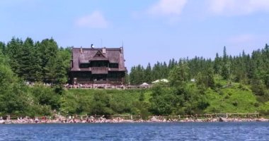 Yaz gününde turistler bir kalabalık ile Polonya Tatras dağ gölünde kulübe görünümü. Timelapse