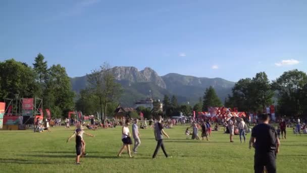 Zakopane, โปแลนด์ มิถุนายน 2019: ผู้คนผ่อนคลายในวันหยุดบนสนามหญ้าสีเขียวในใจกลางเมือง — วีดีโอสต็อก