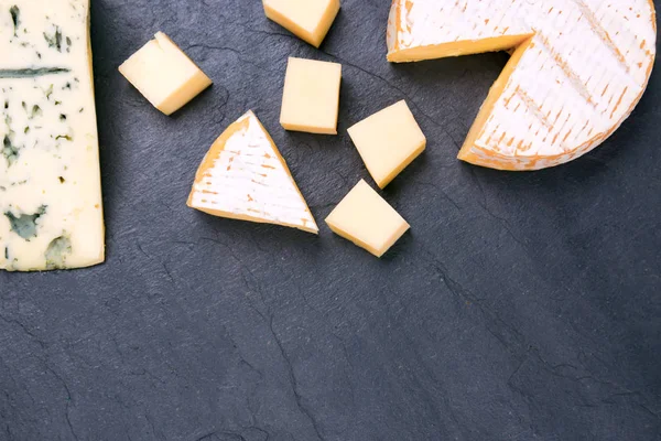 Diferentes tipos de queso en sobre fondo de piedra oscura — Foto de Stock