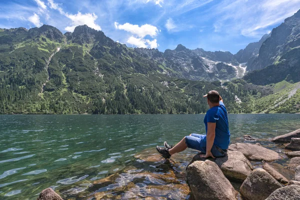 L'uomo ammira il paesaggio montano sul lago — Foto Stock