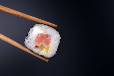 Siyah arka plan üzerinde yakın yemek çubukları ile Sushi rulo