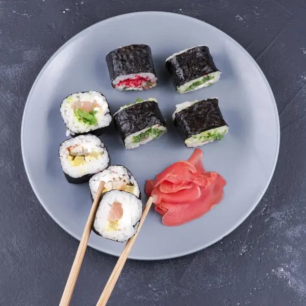 Rollo de sushi con palillos grandes sobre un fondo de plato con vista superior de rollos — Foto de Stock