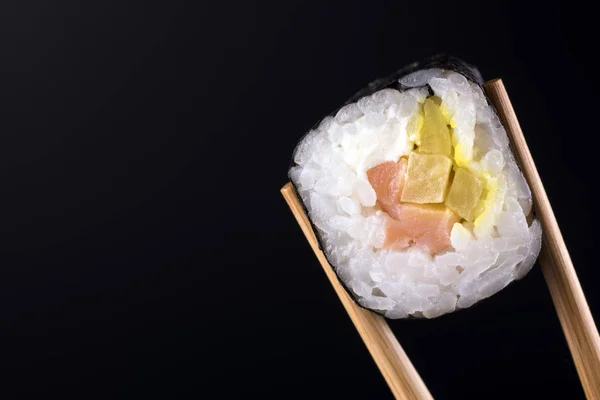 Κοντινό κομμάτι του σούσι roll με σολομό σε μαύρο φόντο — Φωτογραφία Αρχείου