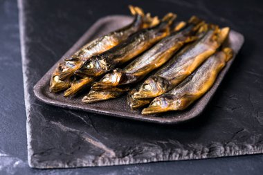 Kapatın. Karanlık arka plan. Masada füme balık var.