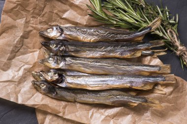 Kapatın. Mutfak kağıdına sarılmış füme balık capelin.