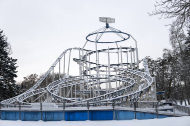 View of snow-covered attractions in the amusement Park on a cold winter day clipart