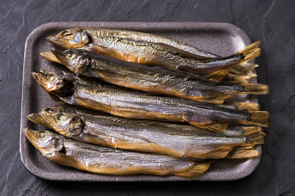 Fecha. Fundo escuro. Capelim de peixe fumado na mesa — Fotografia de Stock