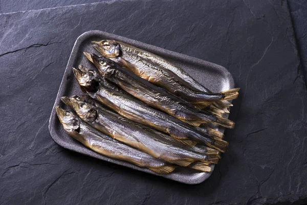 Chiudete. Sfondo scuro. Capelin di pesce affumicato sul tavolo — Foto Stock
