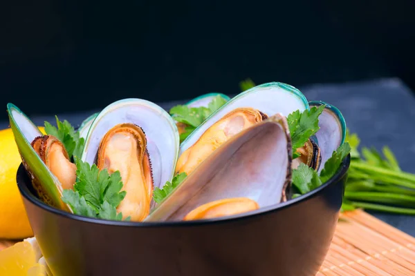 Boiled mussels with parsley and lemon in black dish — Stock Photo, Image