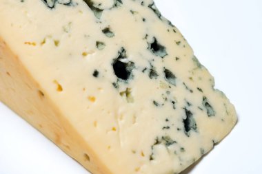 Beyaz arka planda küflü büyük bir peynir parçası.