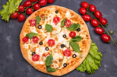 Kapat. Domatesli ve salata soslu koyu arkaplanda pizza.