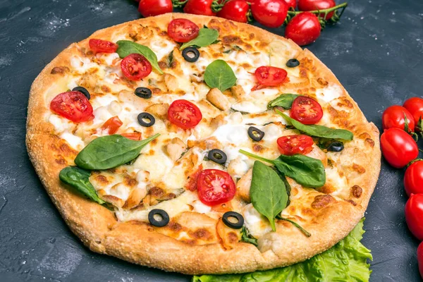 Kapat. Domatesli ve salata soslu koyu arkaplanda pizza.