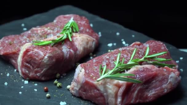 Bife cru com temperos em um fundo escuro — Vídeo de Stock