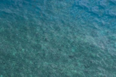 Açık mavi deniz suyu ve denizin dibindeki kayalar.