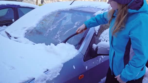 Γυναίκα καθαρίζει το αυτοκίνητο από το χιόνι με ένα πινέλο — Αρχείο Βίντεο
