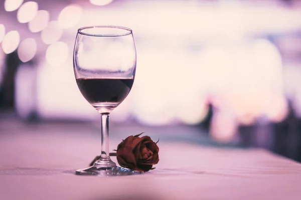 glass of expensive wine at a luxurious dinner with rose in vintage tone.