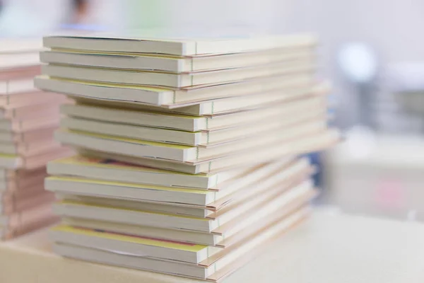 Many new books stacked on a table in a library.