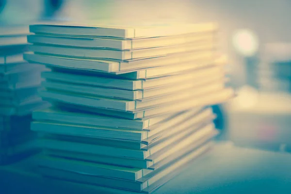 Koyu tonda bir kütüphane tabloda çok sayıda kitap yığılmış.