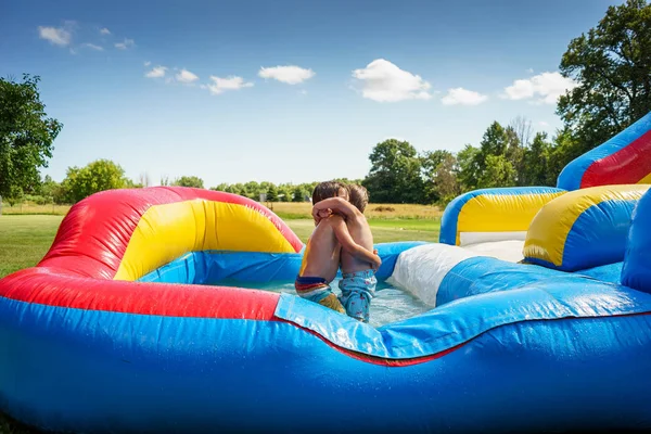 Zwei Jungen Umarmen Sich Auf Einer Aufblasbaren Wasserrutsche — Stockfoto