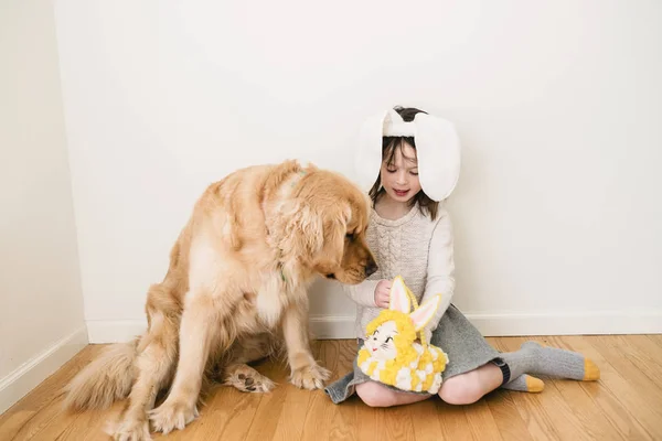 彼女の犬と一緒に床に座ってウサギの耳を身に着けている笑顔の女の子の肖像画 — ストック写真