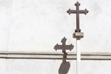 Demir dini haç, gölge ve beyaz duvar, dış.