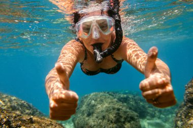 Suyun altında şnorkelle yüzen kadın.