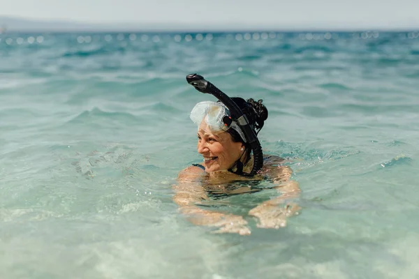 Cheerful woman wearing diving mask and snorkel swimming in water. — Stock Photo, Image