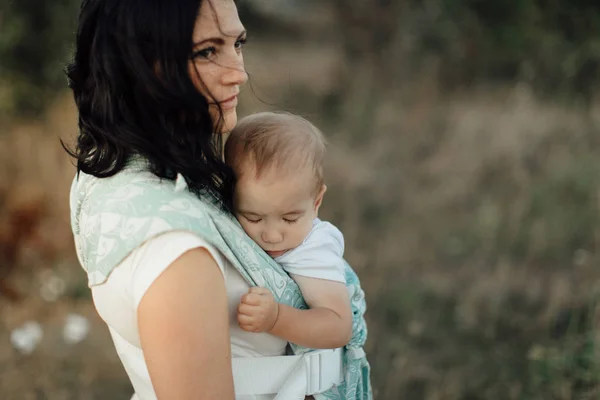 Mère portant son enfant endormi dans le porte-bébé . — Photo