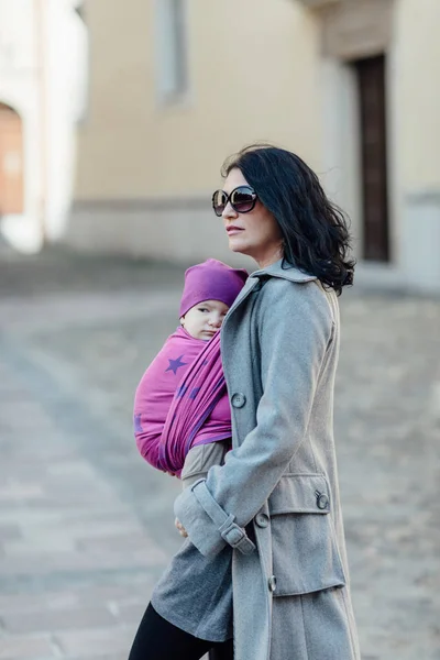 Babywearing mother carrying her child in woven wrap. — Stock Photo, Image