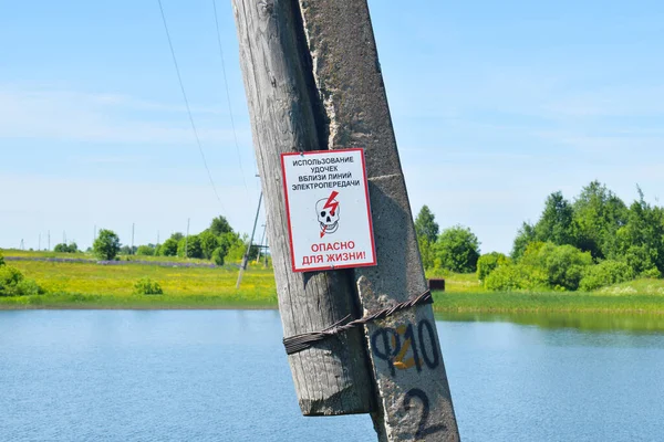 Cartel ruso en un poste para los pescadores con una advertencia sobre el peligro. Poste de madera cerca del lago — Foto de Stock