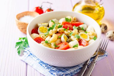 Bıldırcın yumurtası, mozzarella, domates ve mor ahşap zemin üzerine kase Kapari ile makarna salatası. Seçici odak.