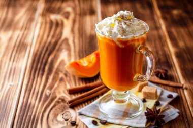 Krem şanti ve cam rustik ahşap zemin üzerine tarçın ile kabak spice latte. Seçici odak.