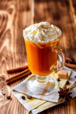 Krem şanti ve cam rustik ahşap zemin üzerine tarçın ile kabak spice latte. Seçici odak.