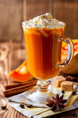 Krem şanti ve cam rustik ahşap zemin üzerine tarçın ile kabak spice latte. Seçici odak.