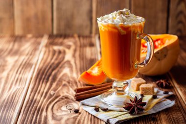 Krem şanti ve cam rustik ahşap zemin üzerine tarçın ile kabak spice latte. Seçici odak.