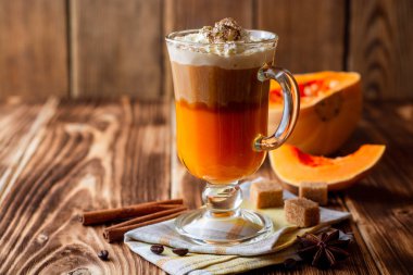 Krem şanti ve cam rustik ahşap zemin üzerine tarçın ile kabak spice latte. Seçici odak.