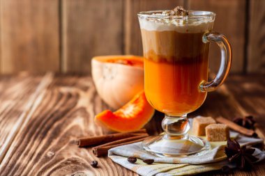 Krem şanti ve cam rustik ahşap zemin üzerine tarçın ile kabak spice latte. Seçici odak.