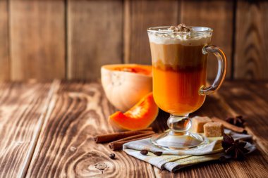 Krem şanti ve cam rustik ahşap zemin üzerine tarçın ile kabak spice latte. Seçici odak.