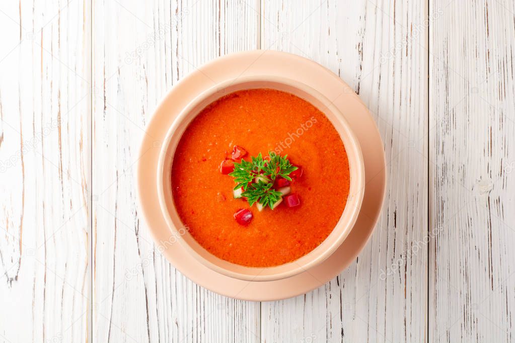 Gazpacho soup in bowl on white wooden background. Traditional spanish dish. Top view.