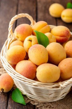 Hasır sepet koyu ahşap zemin üzerine taze kayısı. Seçici odak.