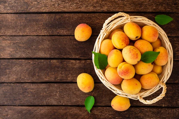 Hasır sepet koyu ahşap zemin üzerine taze kayısı. Üstten görünüm. Kopya alanı.